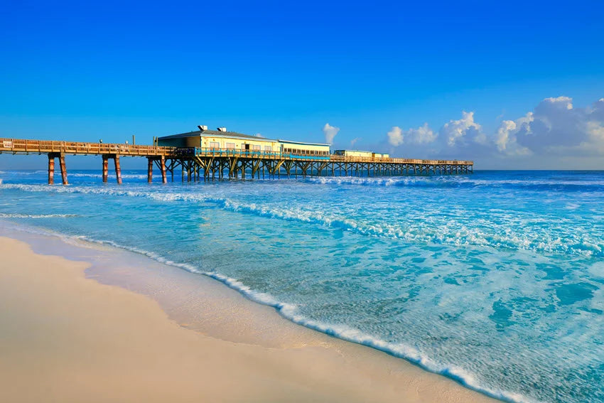 Ocean pier, blue water and sandy shoreline